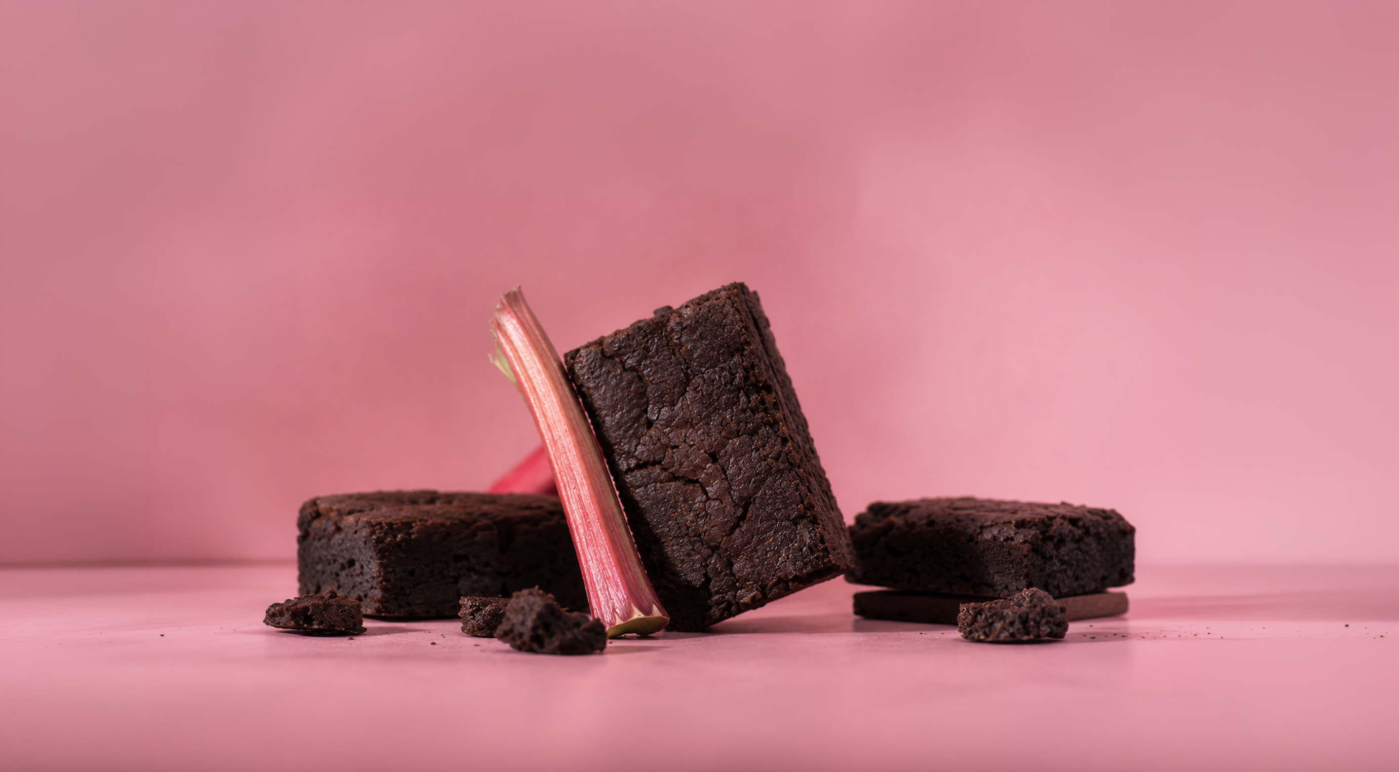 Chocolate brownies and rhubarb against a pink background