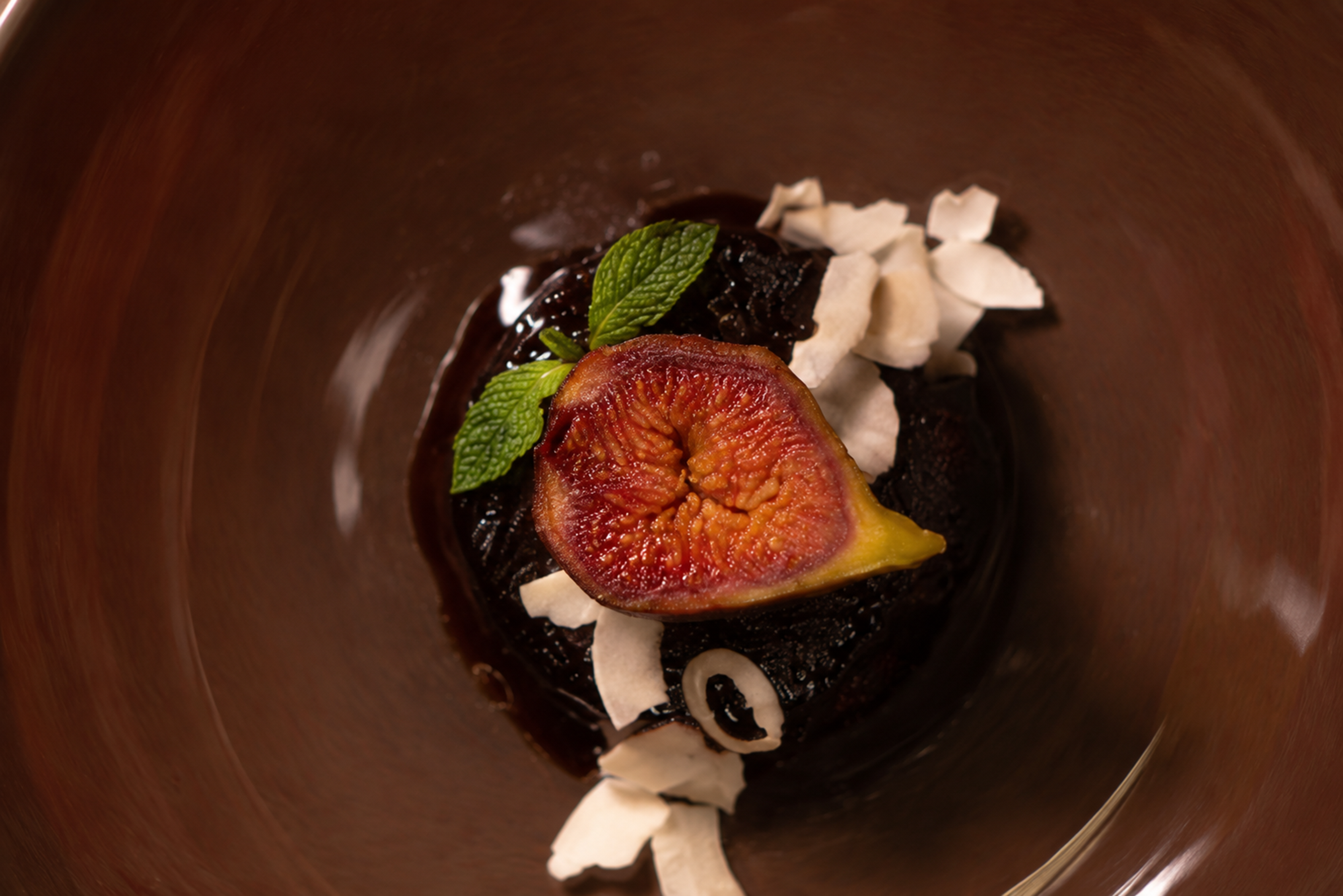 Chocolate pudding topped with fig, mint and cream