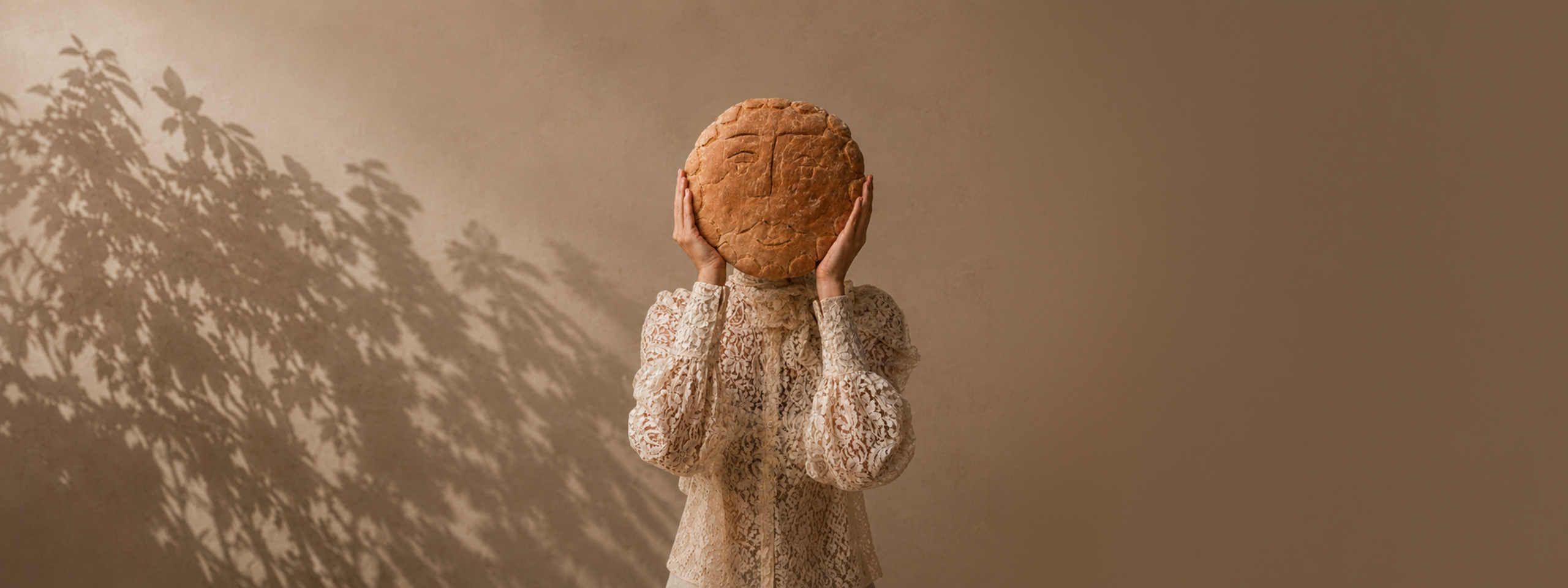 Woman holding an artisan bread loaf in front of her face