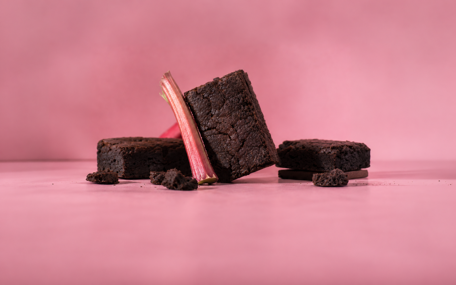 Chocolate brownies and rhubarb against a pink background